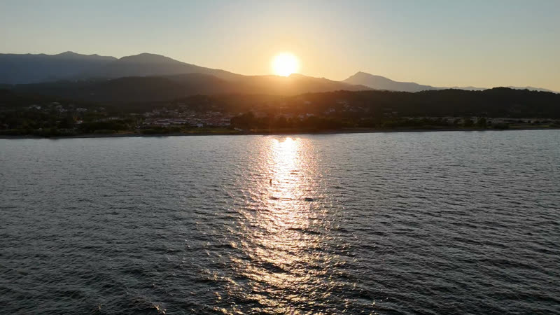 Coucher de soleil sur l’eau, montagnes en silhouette
